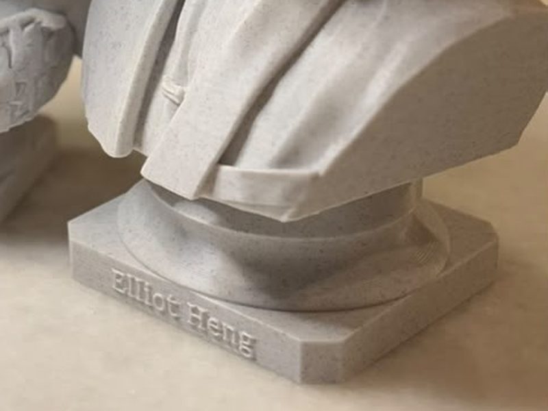 Close-up of a statue base with the name Elliot Heng raised on the front
