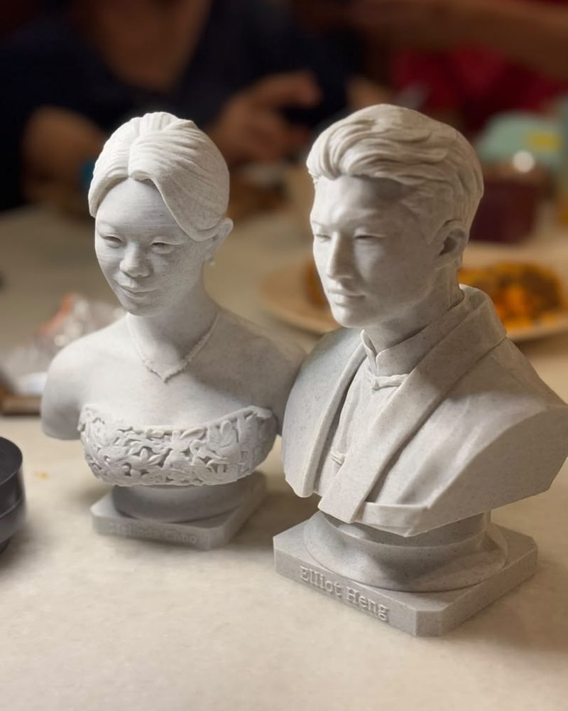 Two marble-effect PLA statue caricatures with names on their bases